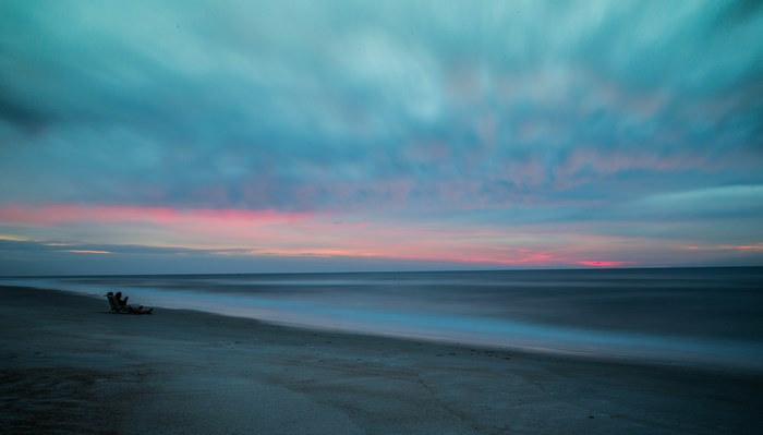 Couple relaxing on beach at sunrise with long exposure