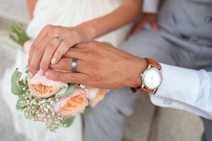 Close-up of Newlywed Couple Holding Hands with Flowers