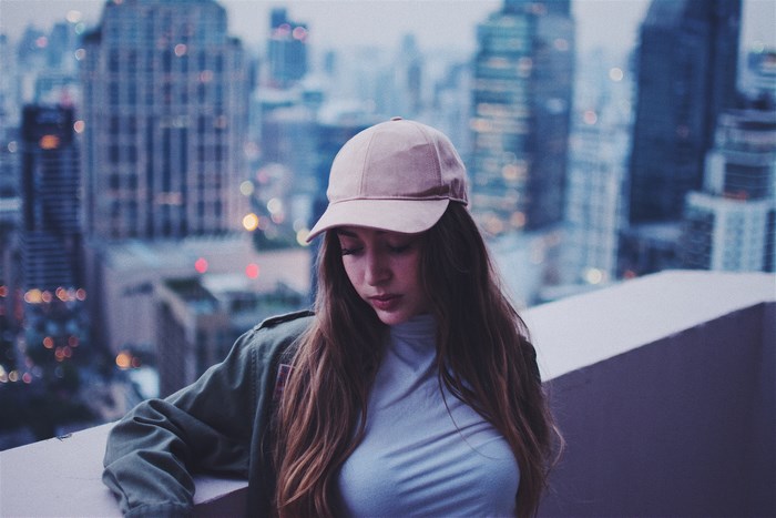 Woman wearing a cap on a balcony overlooking city