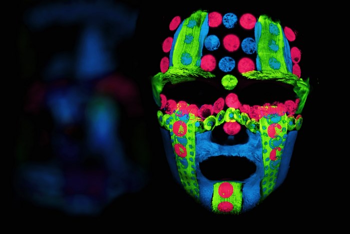 Person with neon face paint in dark