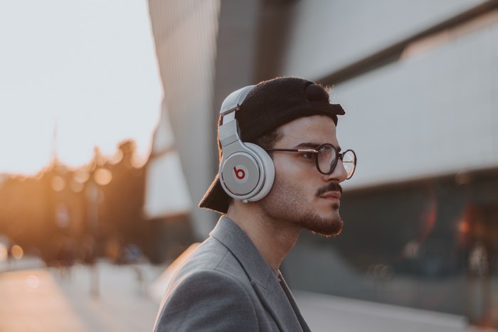 Man wearing Beats headphones and glasses outdoors at sunset