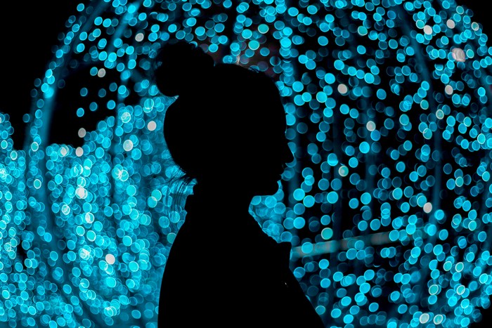Silhouette of a woman against blue bokeh lights