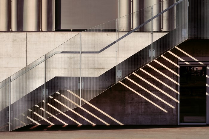 Modern concrete building with metal staircase and shadows