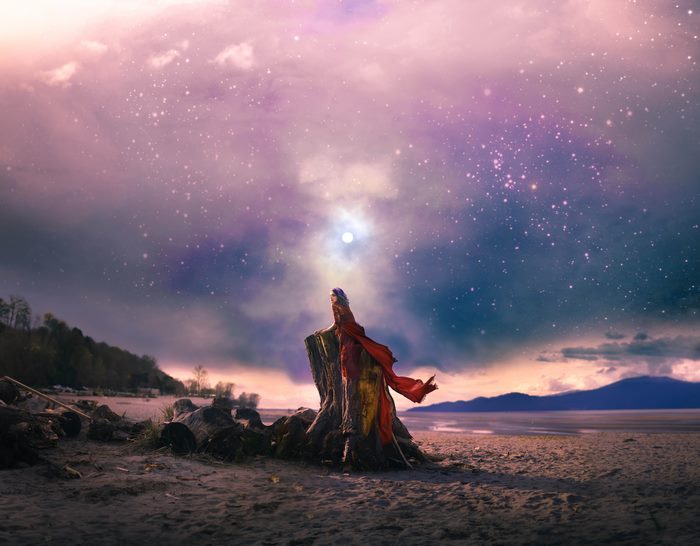 Person in Red and Yellow Fabric on Tree Stump Under Starry Sky