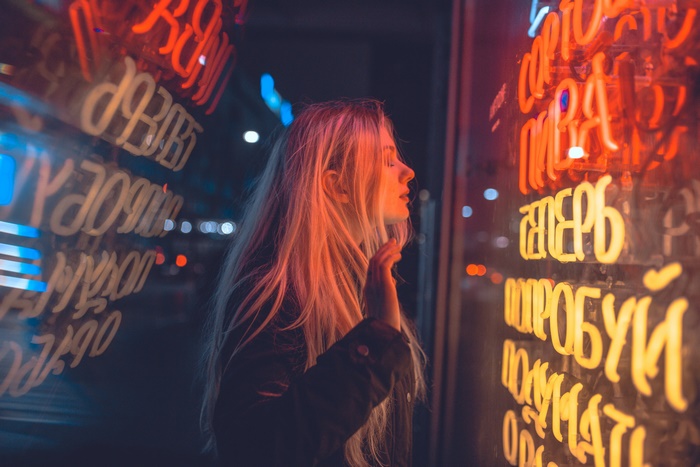 Woman looking at neon signs at night