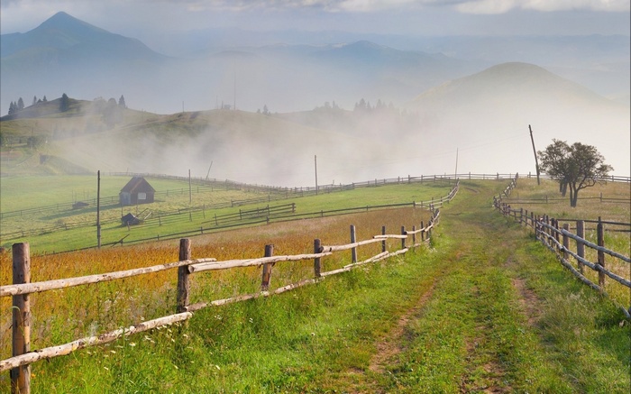 Mountain landscape with a dirt road and wooden fence