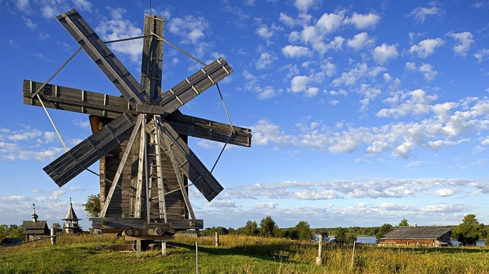 Wooden windmill and traditional buildings under a blue sky