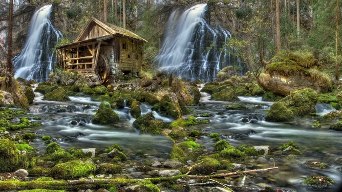 Wooden mill beside a waterfall in a forest
