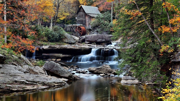Old mill with water wheel by a waterfall in autumn