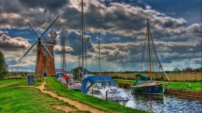 Windmill and boats docked by a canal