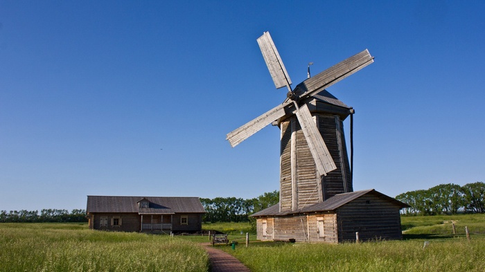 Wooden windmill and house in a grassy field