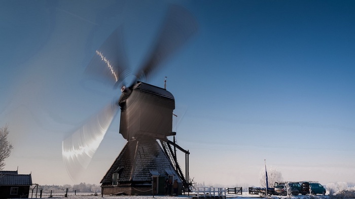Windmill with spinning blades in a snowy landscape