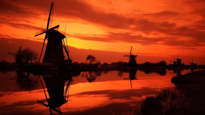 Windmills reflected in water at sunset