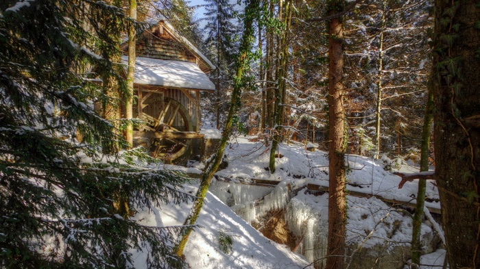 Snowy forest with a wooden mill and water wheel