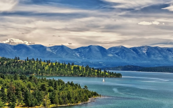 Sailboat on a lake with mountains and forest