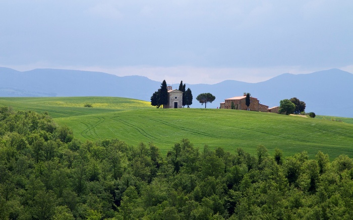 Chapel and farmhouse on rolling green hills in Tuscany