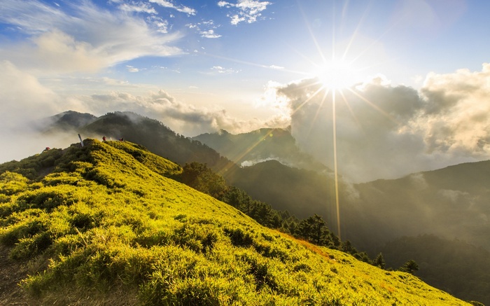 Sunlit mountain ridge with clouds and hikers