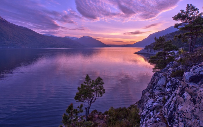 Purple sunset over a calm lake and mountains