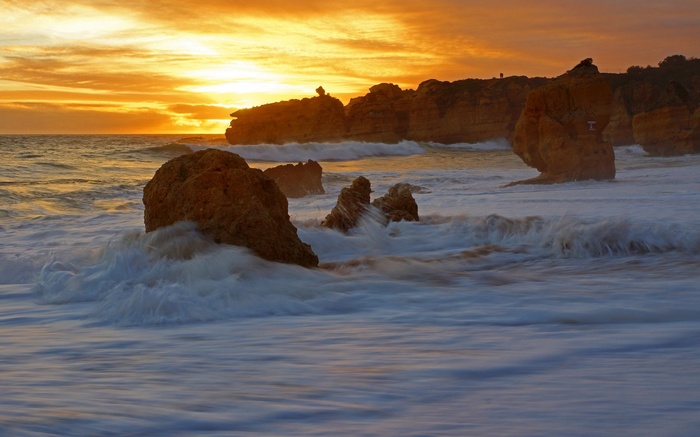 Waves crashing on rocks at sunset