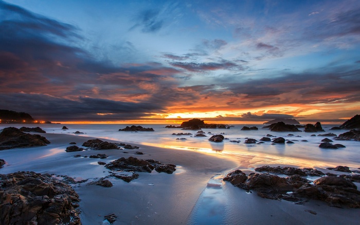 Sunset over a rocky beach with calm ocean waves