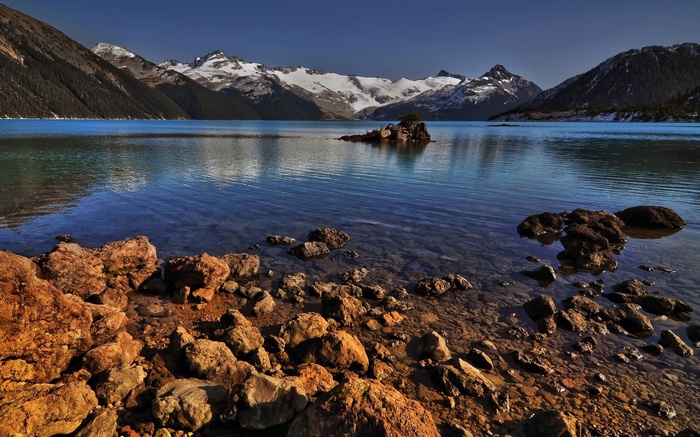 Rocky lake shore with snow-capped mountains