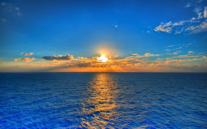Sunset over the ocean with clouds and sun rays