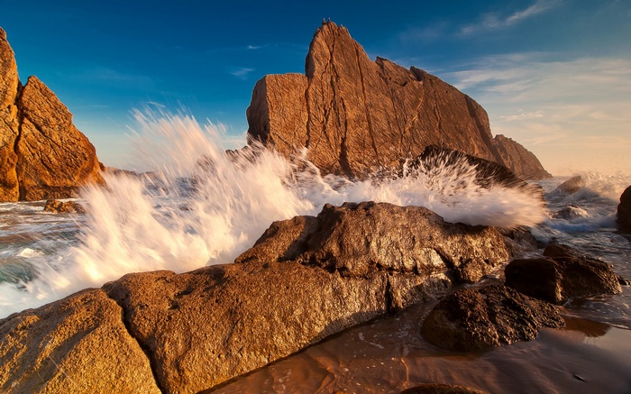 Waves crashing on rocky shore at sunset