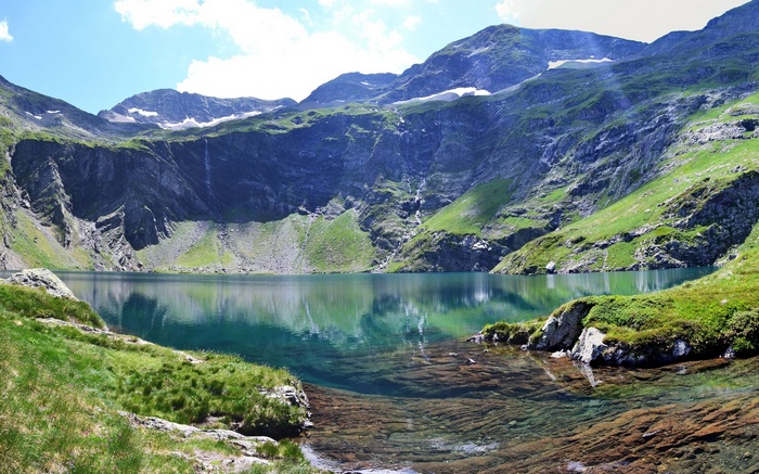 Mountain lake with rocky shore and green slopes