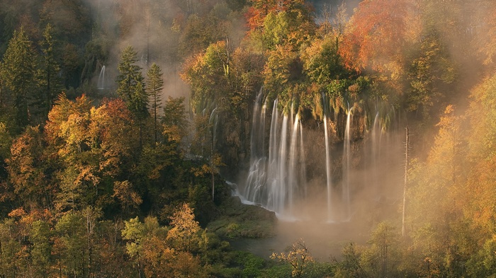 Waterfall in autumn forest with mist
