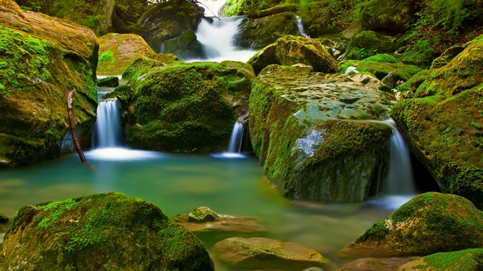 Mossy rocks and waterfalls in a forest stream