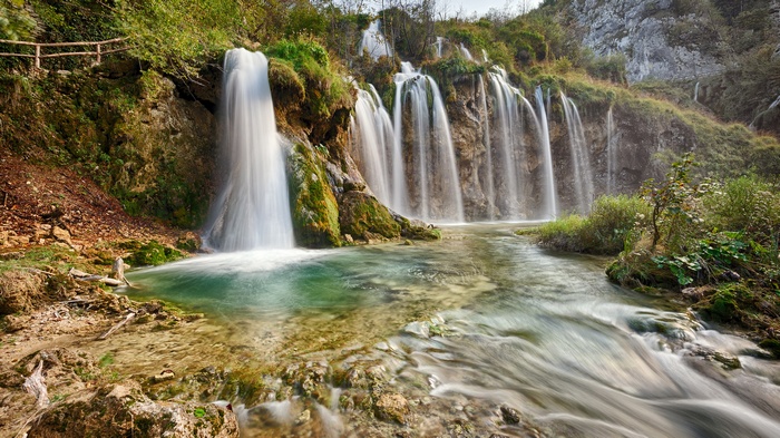 Waterfalls cascading into a turquoise pool in a forest
