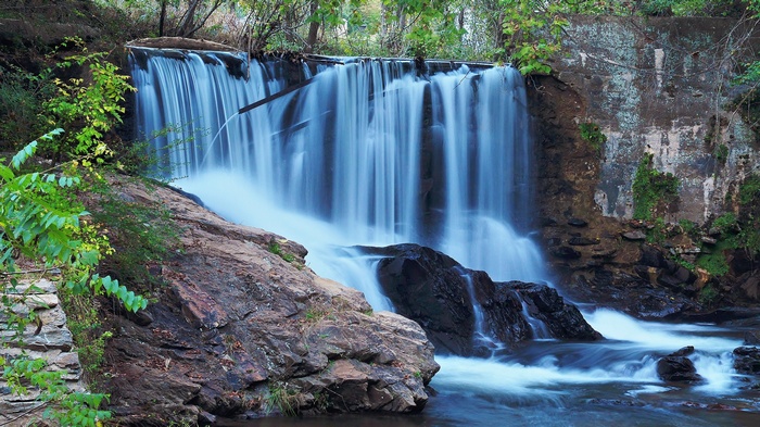 Waterfall cascading over rocks and concrete structure