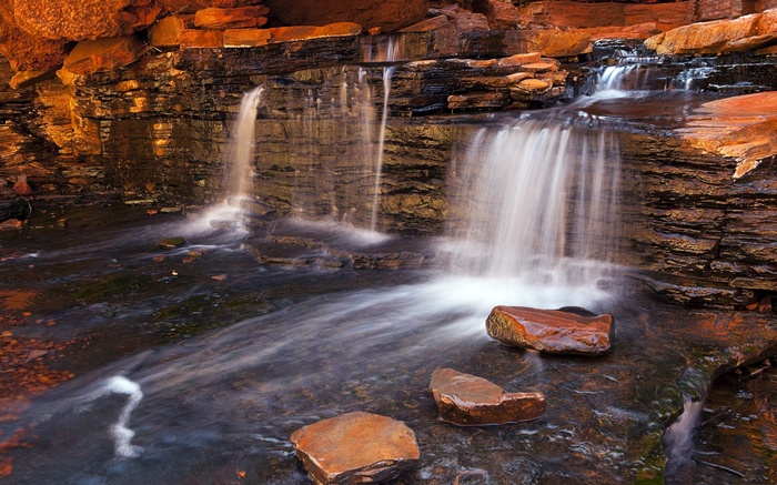 Waterfalls cascading over layered rocks