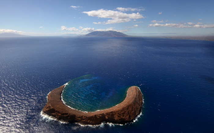 Island in the ocean with distant mountains