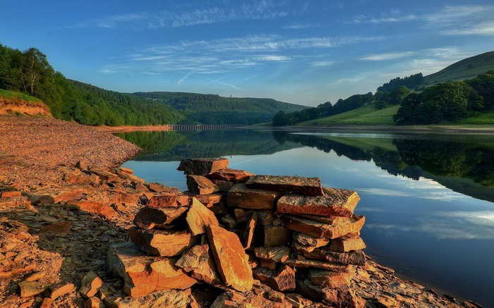 Rocky shore of a reservoir with a dam in the distance