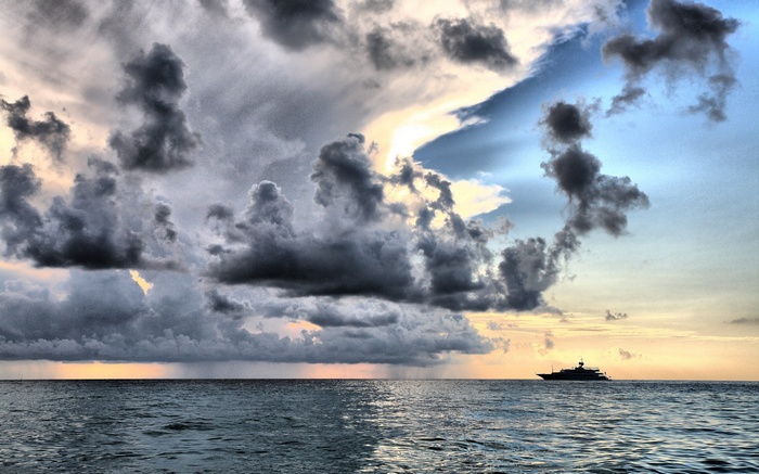 Yacht sailing on the ocean under dramatic storm clouds