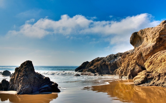 Rocky beach with ocean waves and blue sky