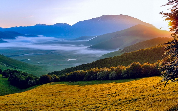 Sunrise over misty mountains and green valleys