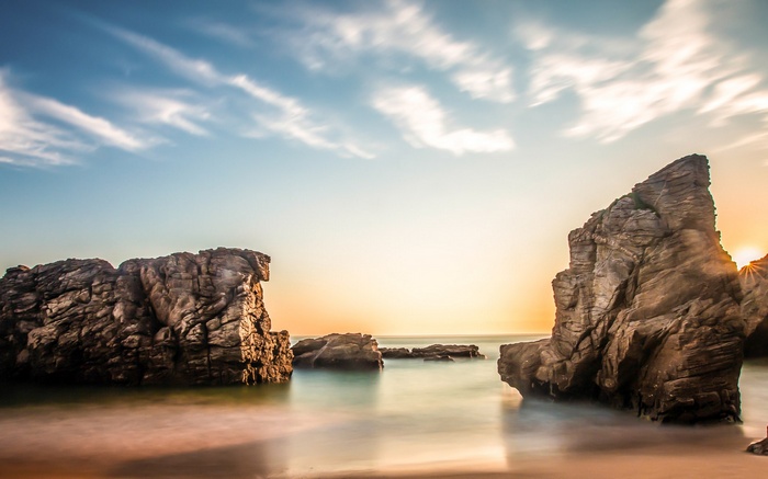 Rocky beach with ocean waves at sunset
