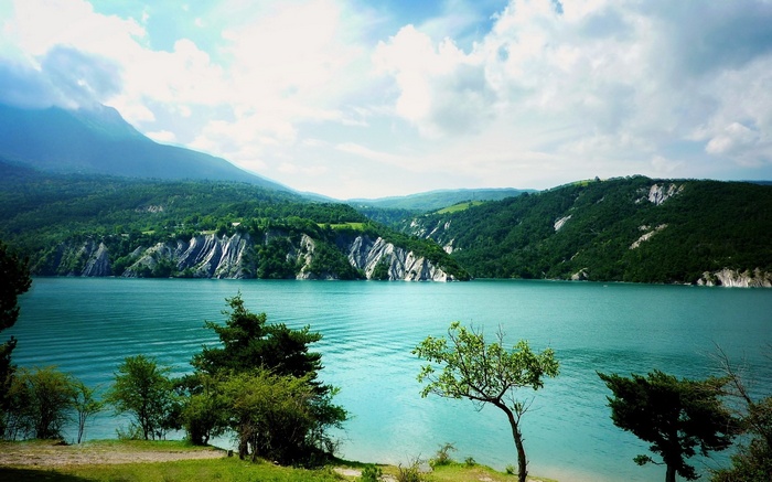 Turquoise lake surrounded by green mountains and trees