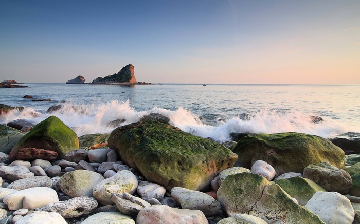 Rocky beach with waves crashing and rock formations in the sea
