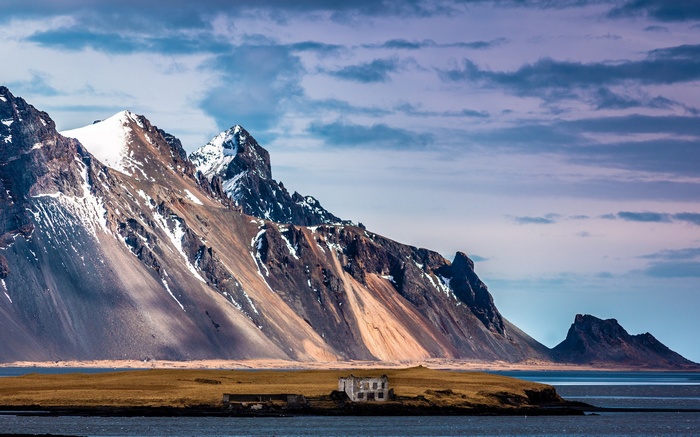Ruined building on a grassy island with mountains and sea