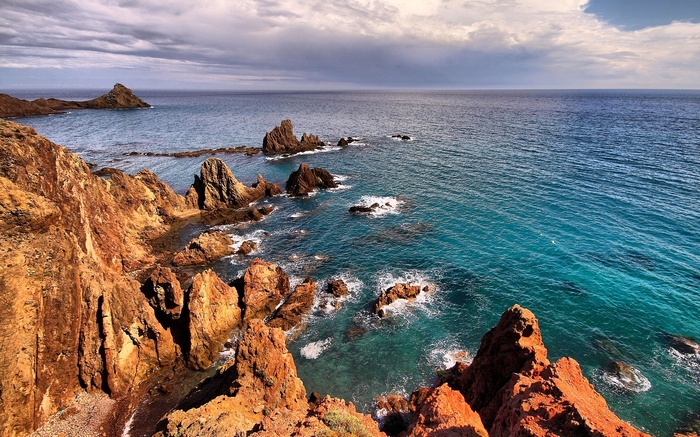 Rocky coastline with turquoise ocean and dramatic clouds