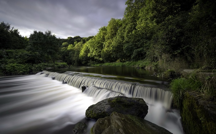 Waterfall flowing over rocks with trees in the background