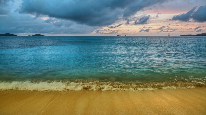 Ocean waves on a sandy beach at sunset