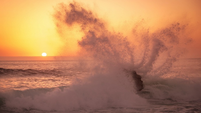 Sunset over the ocean with a crashing wave
