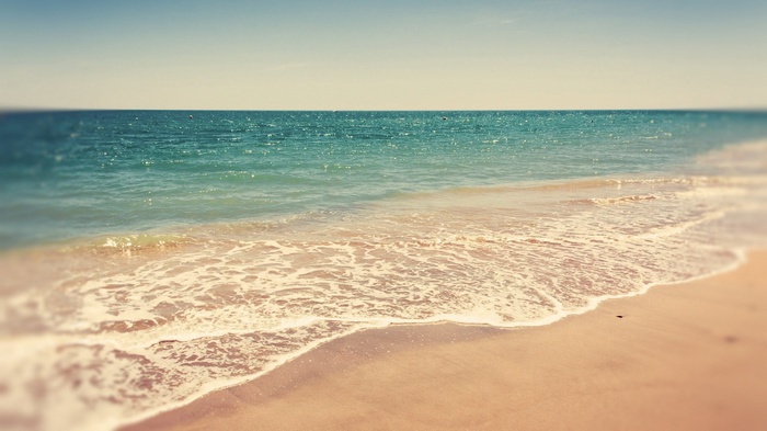 Ocean waves gently lap onto a sandy beach