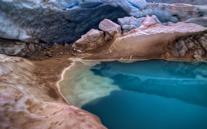Glacier cave with blue water and ice formations