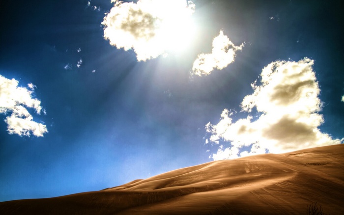 Sunlight beams through clouds over sand dunes