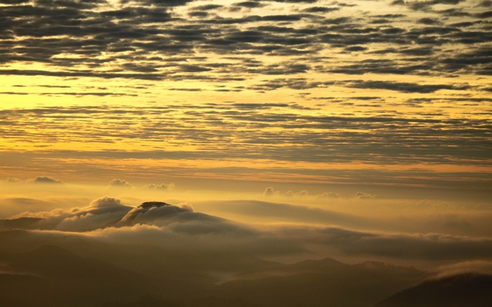 Sunrise over misty mountains with layered clouds